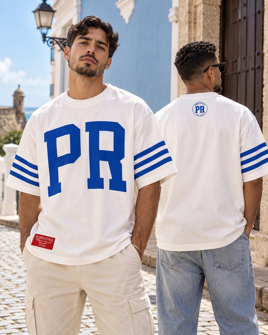 Two men wearing the white and blue Men's PR Varsity Stripe Tee by Kokii Style in Old San Juan – front and back view