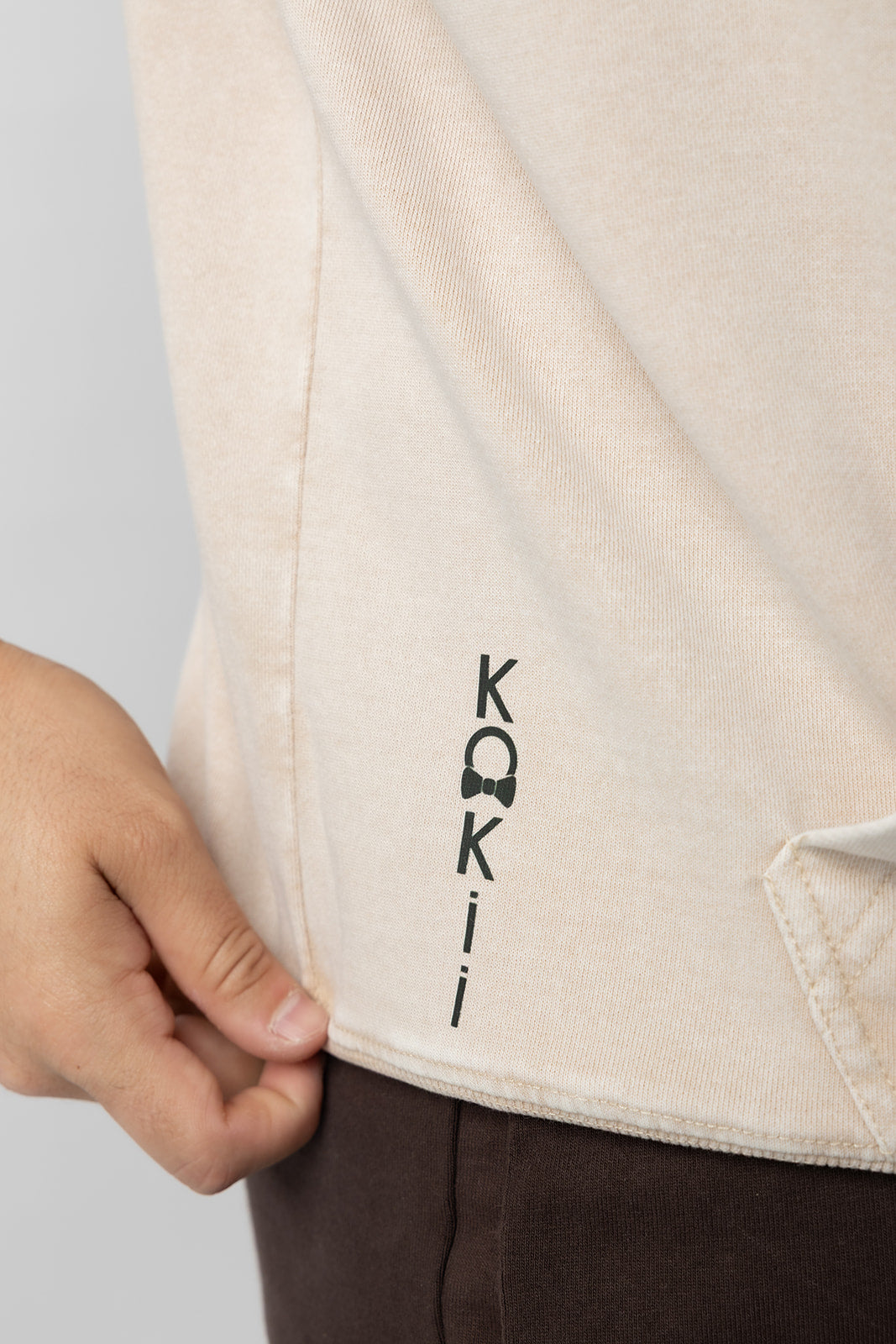 Vertical KOKii logo print near the hem of the washed sand Lucas 1:37 hoodie