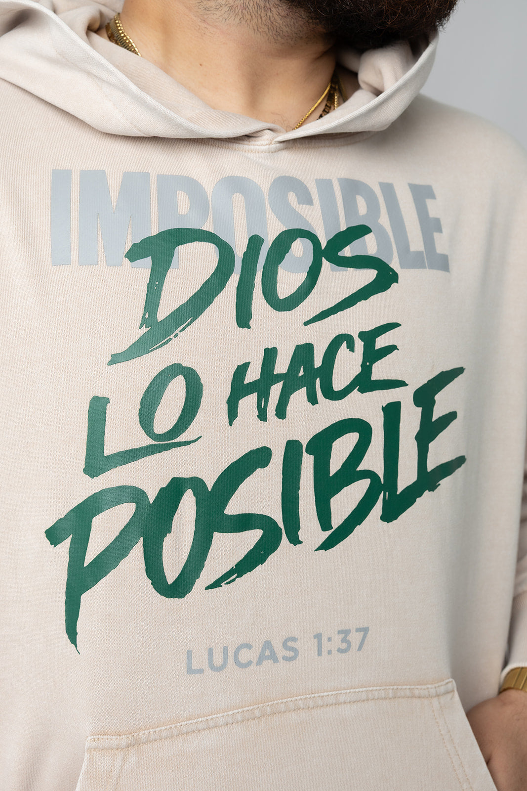 Close-up of the washed sand Dios Lo Hace Posible hoodie with green lettering over Imposible and Lucas 1:37